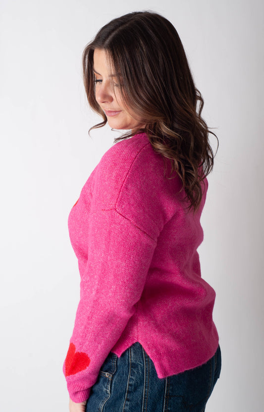 Woman wearing a bright pink sweater with red cuffs and hem against a white background