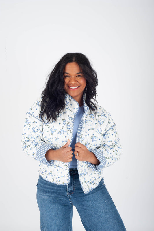 Woman wearing a floral jacket over a striped shirt with a plain background