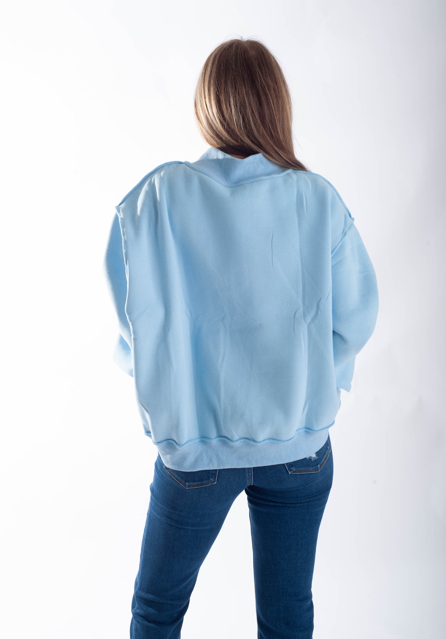 Person wearing a light blue sweatshirt and jeans on a white background