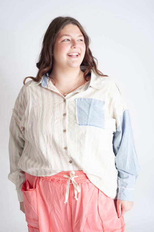 Person wearing a light-colored shirt with a patch and pink pants on a white background