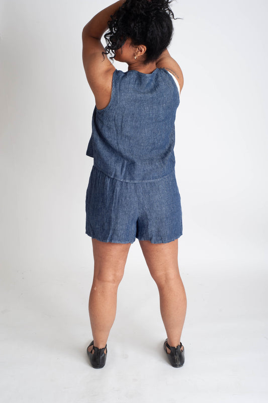Person wearing a blue denim romper on a white background