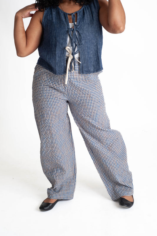 Person wearing a blue sleeveless top and checkered pants on a white background