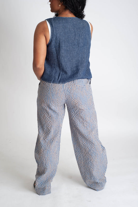 Person wearing a blue sleeveless top and checkered pants on a white background