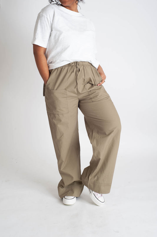 Person wearing beige wide-leg pants and a white top on a white background