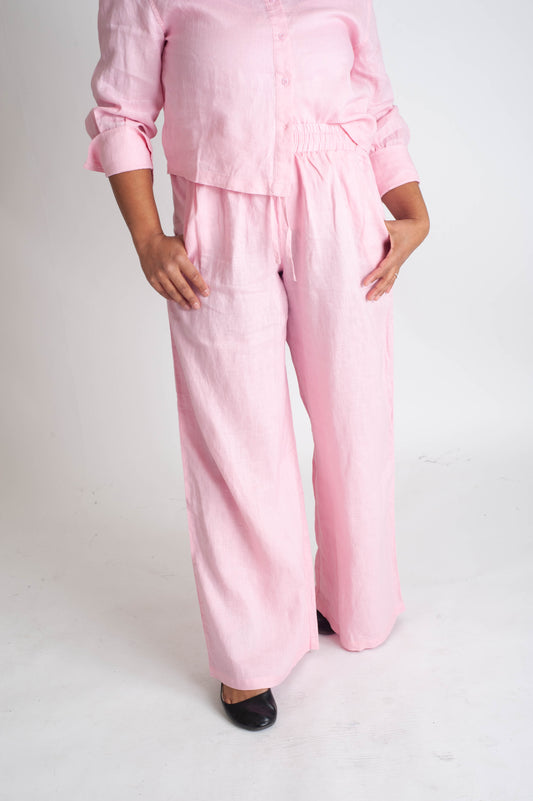 Person wearing a pink outfit with wide-leg pants on a white background
