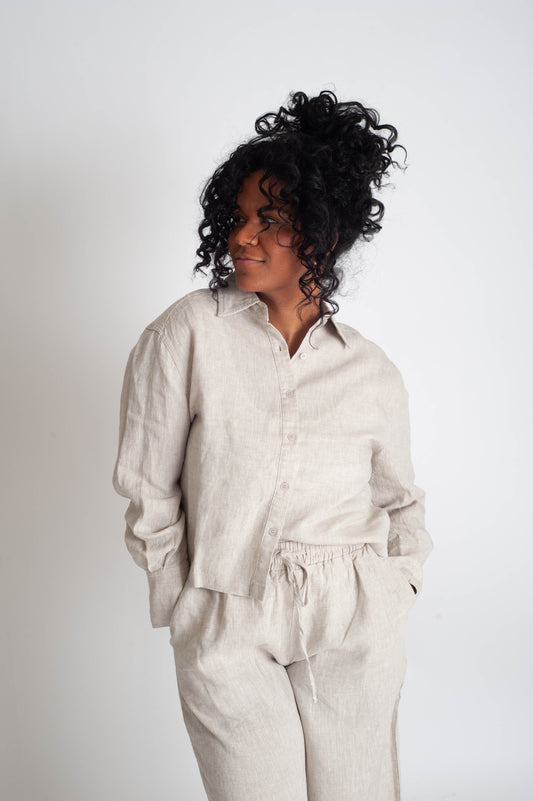 Woman wearing a light beige linen shirt and pants on a white background