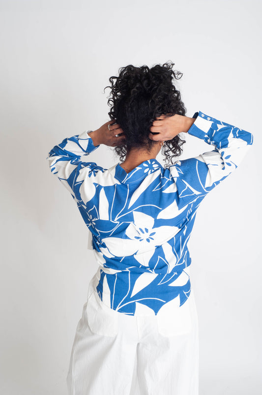 Person wearing a blue and white floral blouse against a plain background