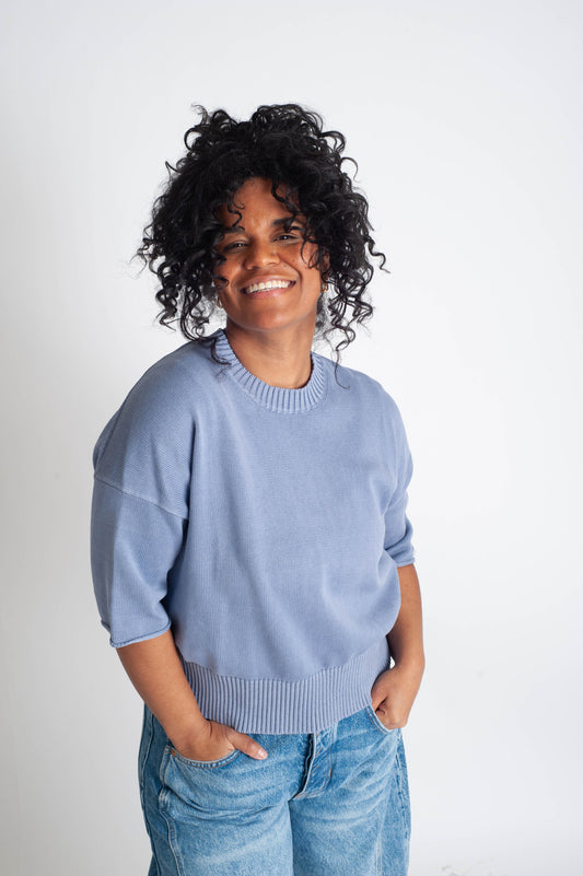 Person wearing a light blue sweater and jeans against a white background