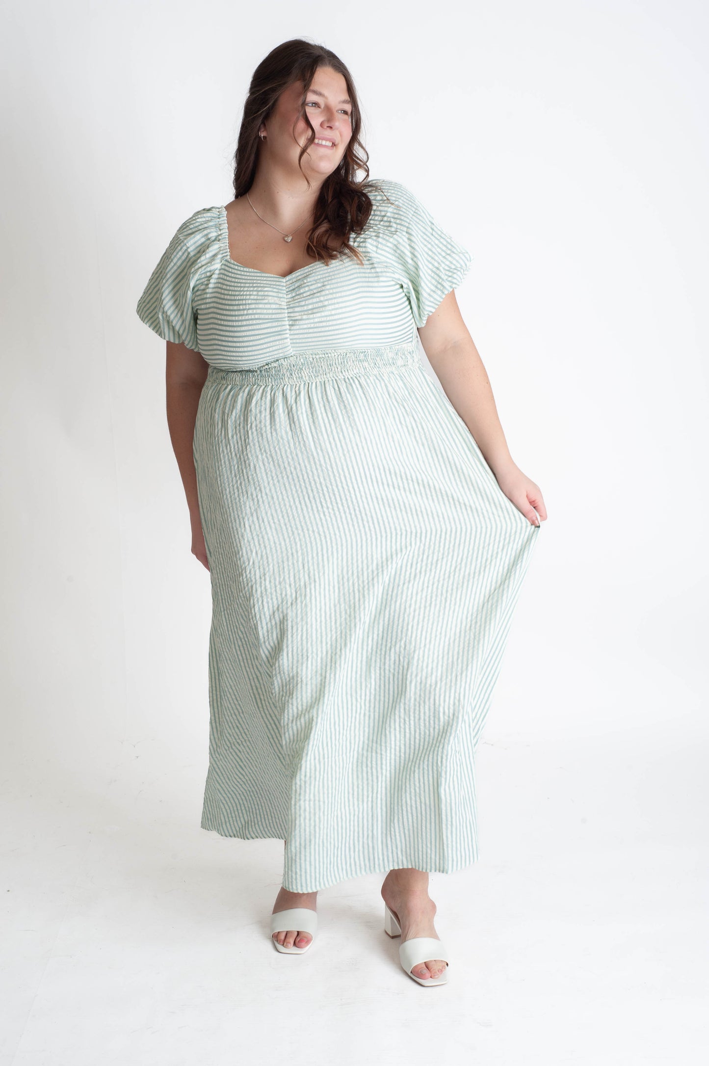 Woman wearing a green and white striped dress on a white background