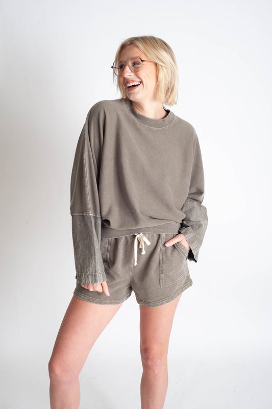 Woman wearing a matching olive green sweatshirt and shorts set on a white background