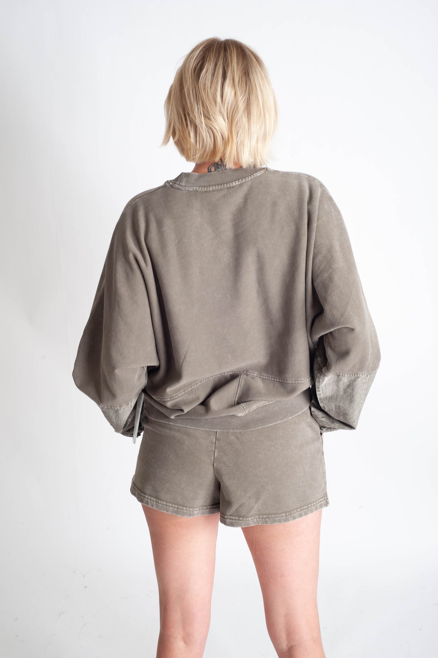 Person wearing a green oversized shirt and shorts set on a white background