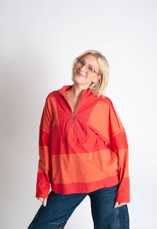 Person wearing a red and orange pullover with a plain background