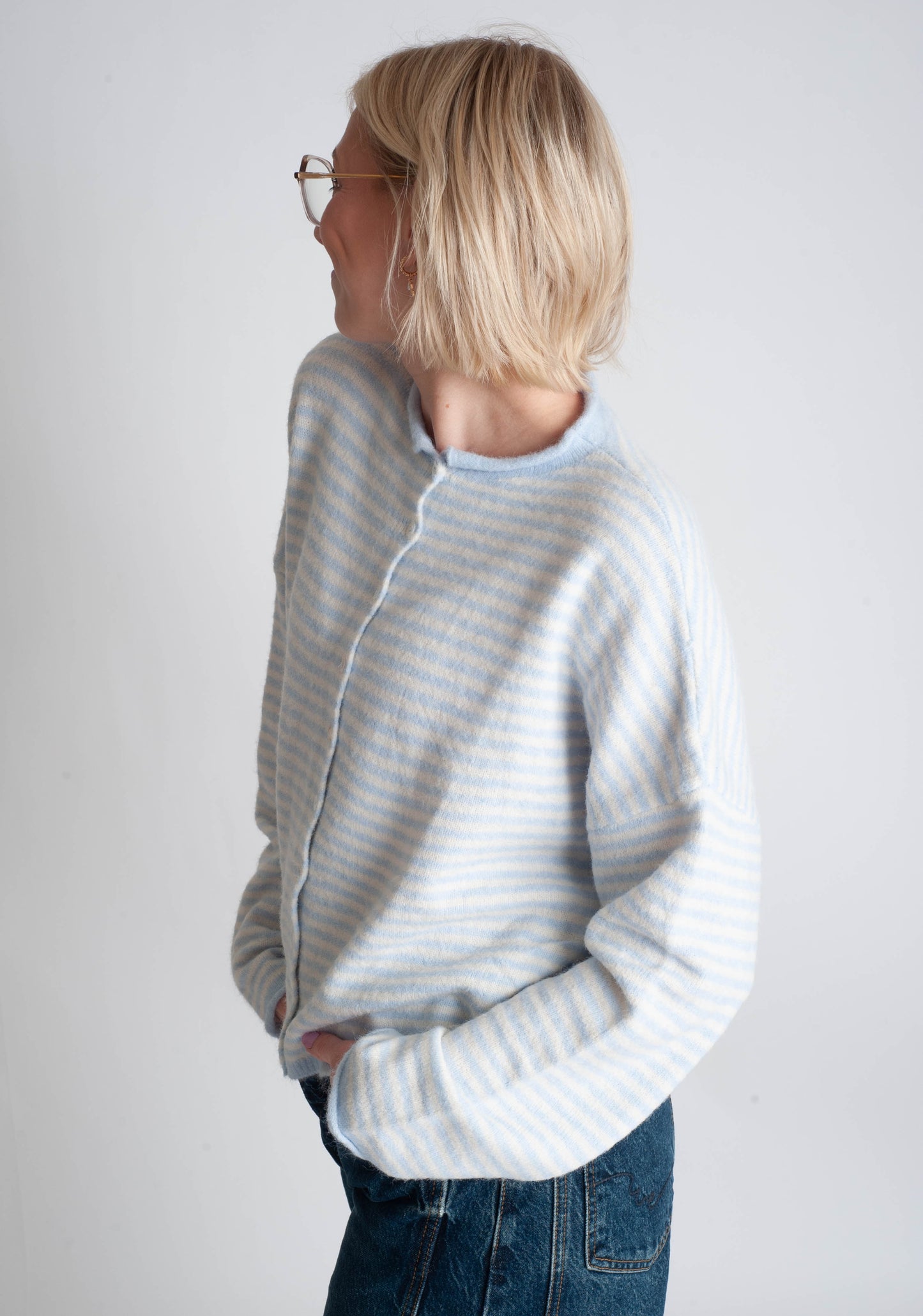 Person wearing a light gray and white striped sweater against a plain background