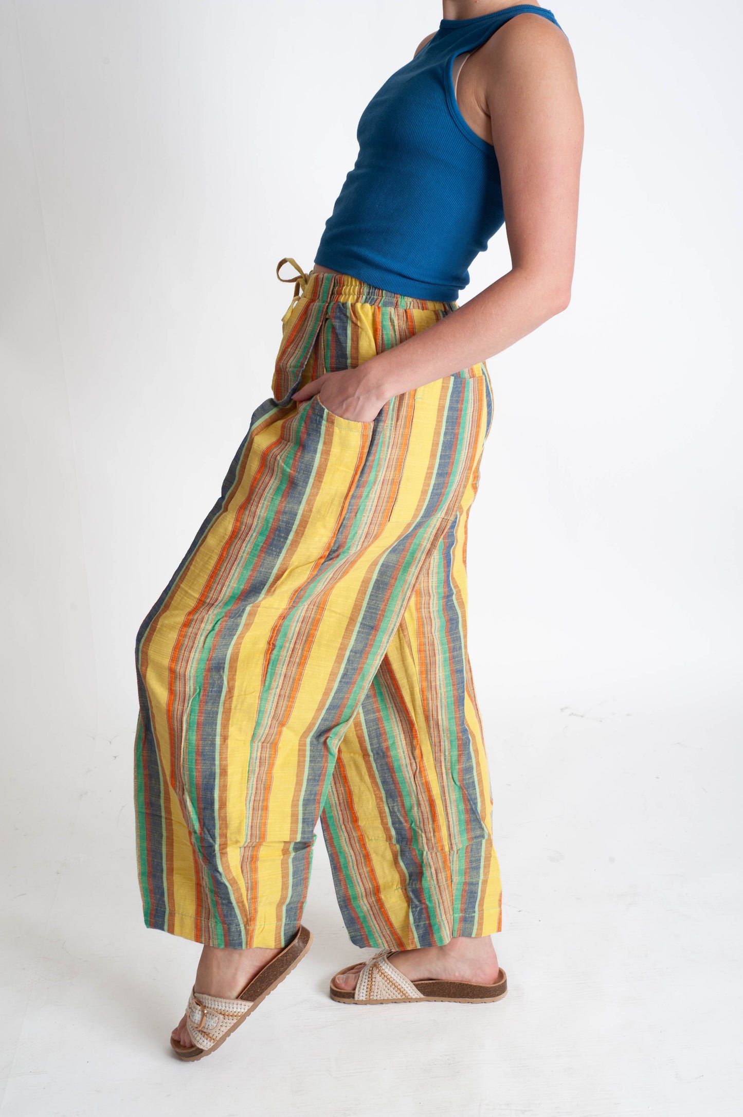 Person wearing colorful striped pants and a blue top on a white background