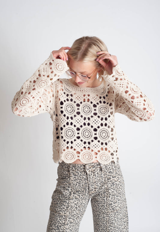 Person wearing a patterned sweater and pants on a plain background