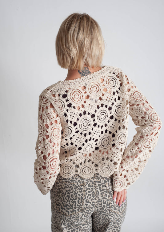 Person wearing a crochet sweater with a white background