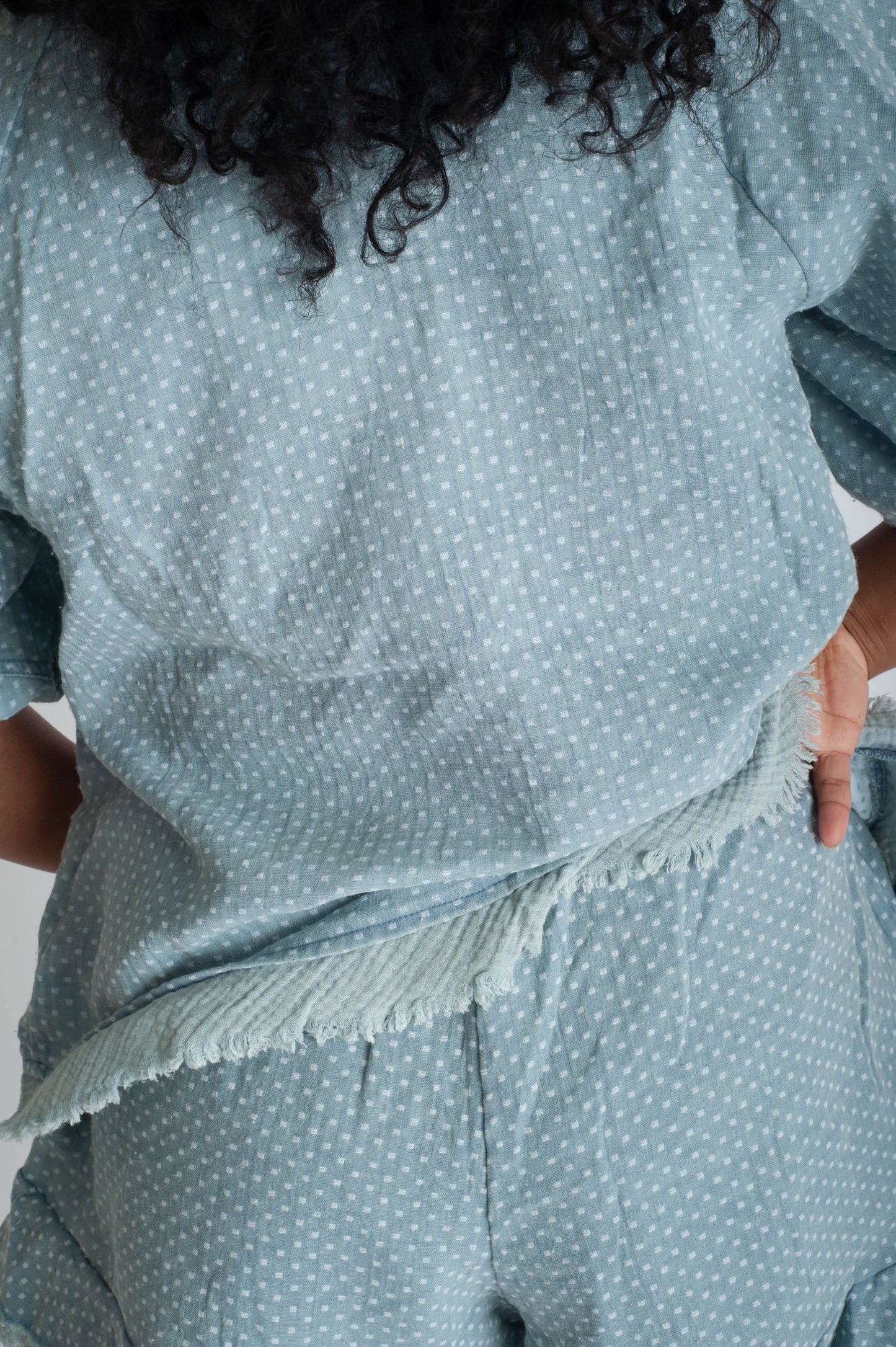 Person wearing a teal polka dot outfit with fringe details