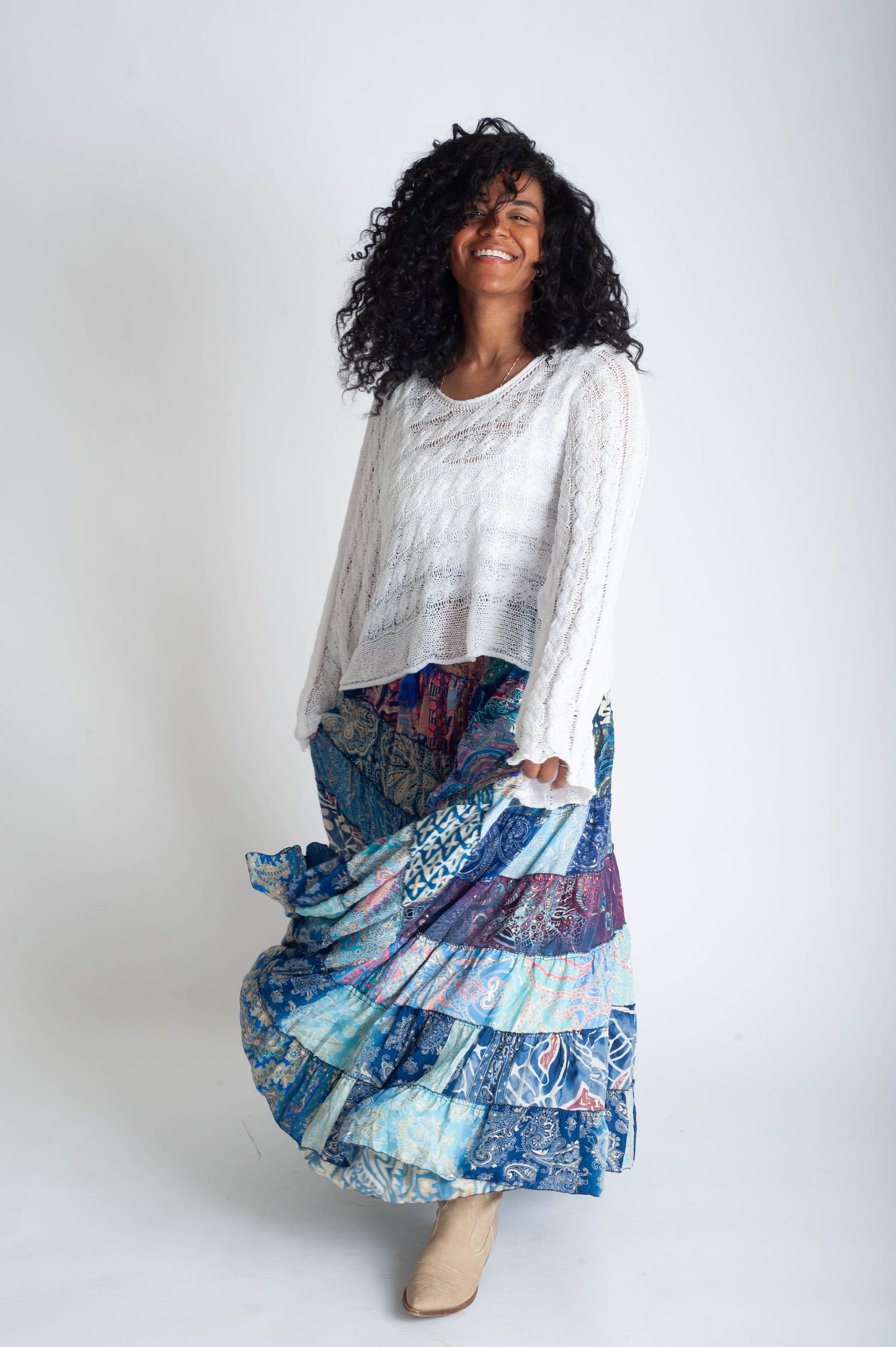 Woman wearing a white top and colorful patchwork skirt on a white background