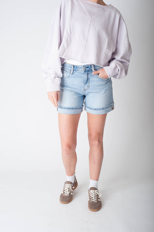 Women wearing long denim shorts and a purple sweater.