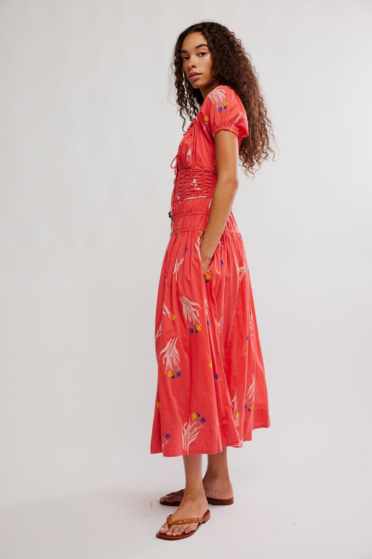 Woman wearing a coral dress with white floral patterns on a white background