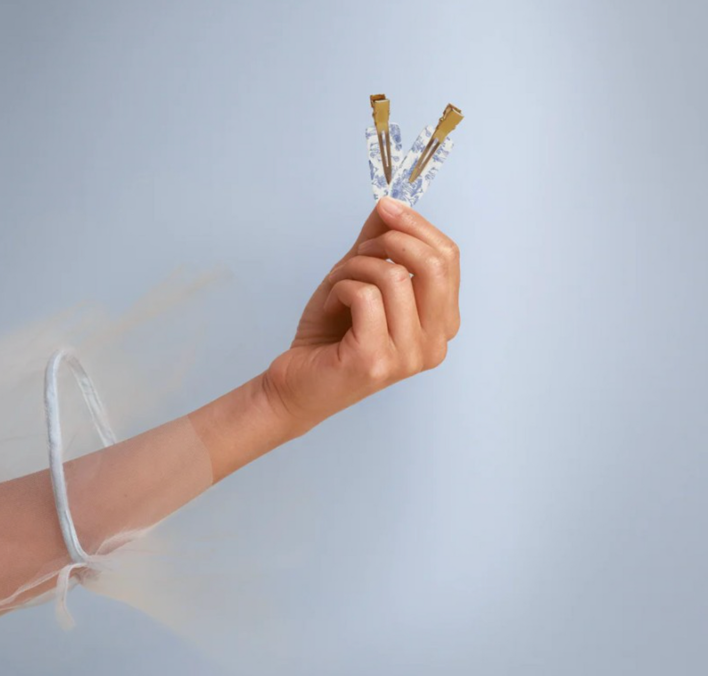 Hand holding a small object against a light gray background