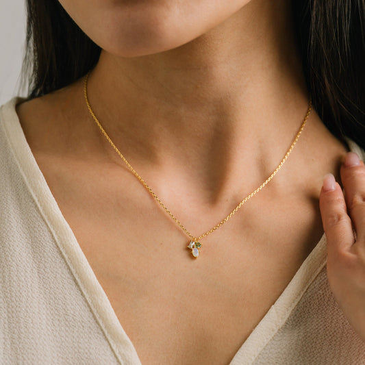 Close-up of a person wearing a gold necklace with a pendant.