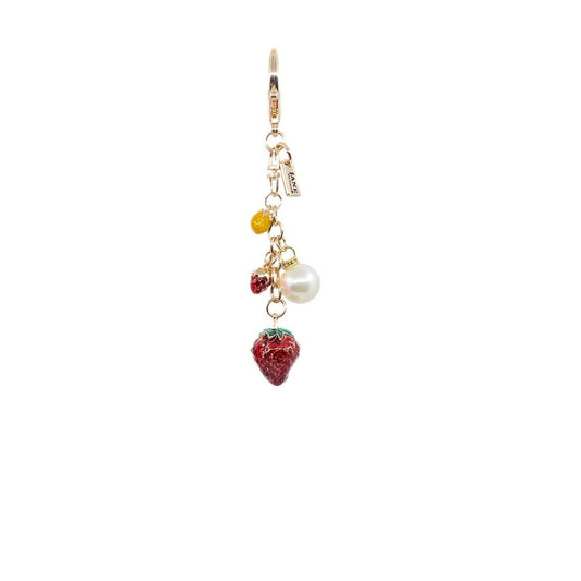 Strawberry-shaped keychain with pearl and gold elements on a white background