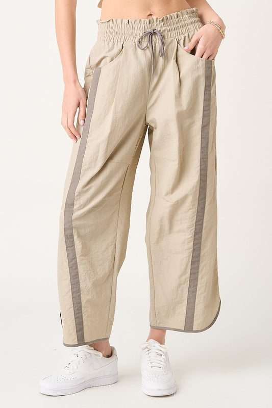 Beige pants with gray stripes worn by a person on a white background