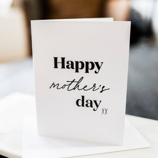 A simple Mother's Day card with black lettering on a white background, folded card with a white envelope, placed on a white surface.