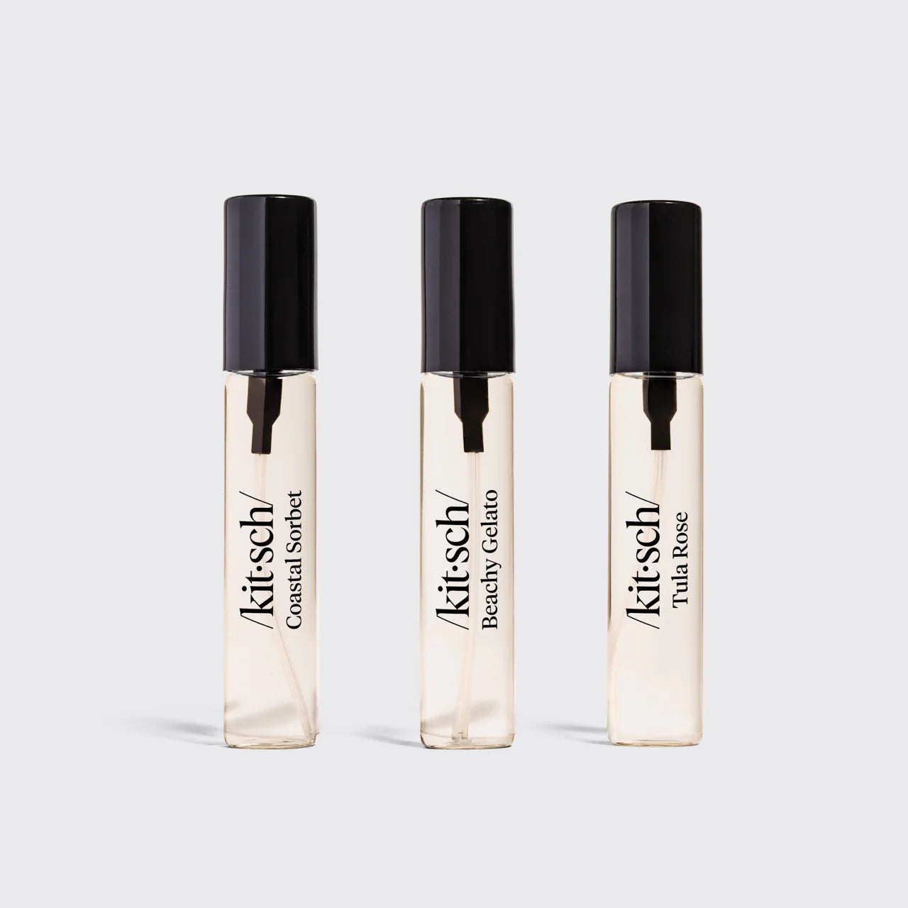 Three Kitsch perfume bottles on a light gray background
