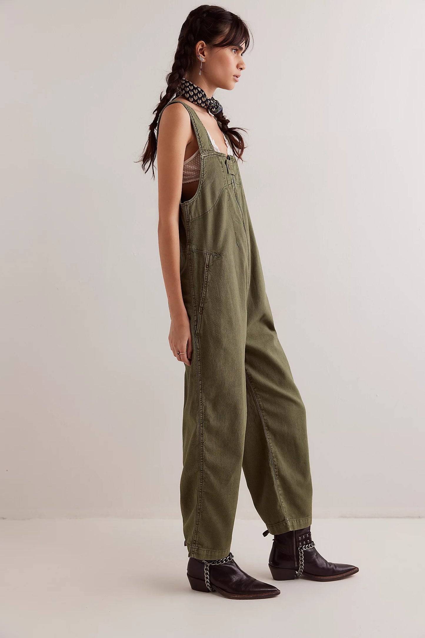 Woman wearing green overalls and black boots on a white background
