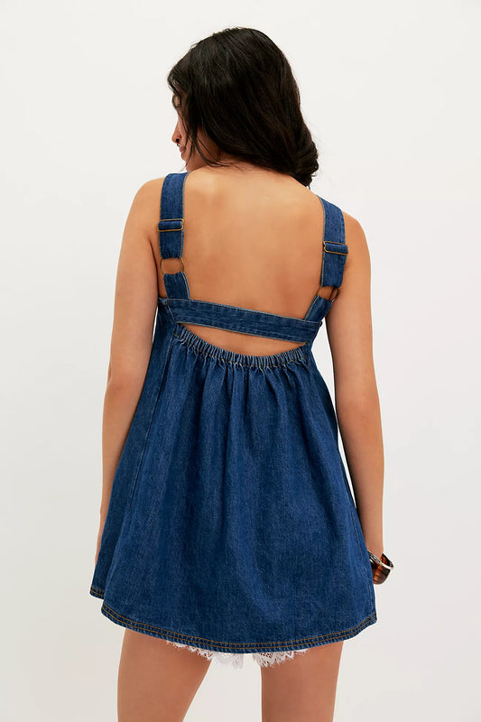 Woman wearing a blue denim dress with cut-out back on a white background