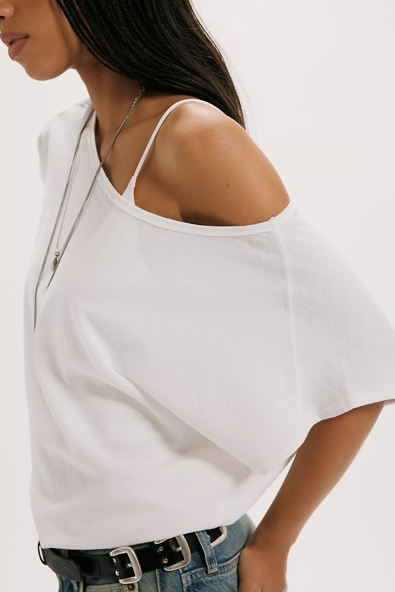 Woman wearing a white sleeveless top with a zipper detail on a plain background
