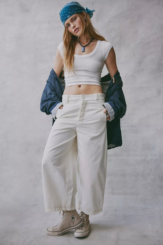 Person wearing a white crop top, beige pants, and a blue bandana against a gray background