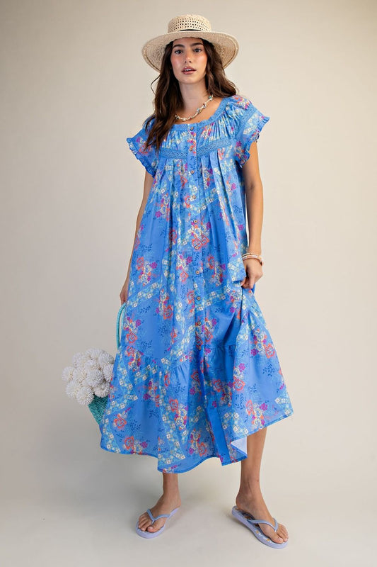 Woman wearing a blue floral dress and straw hat on a plain background