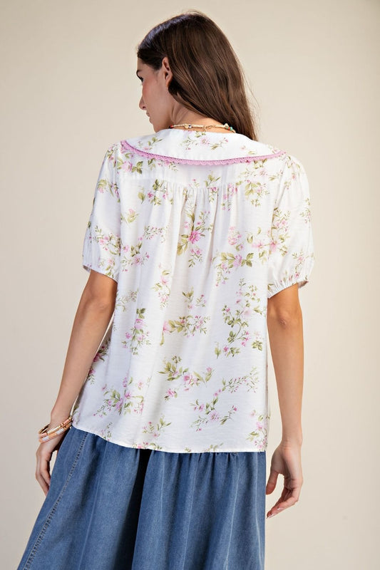 Woman wearing a floral blouse and blue skirt against a beige background