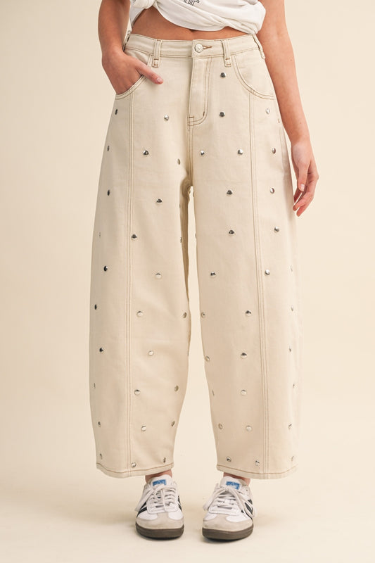 Beige pants with small heart studs worn by a person on a beige background