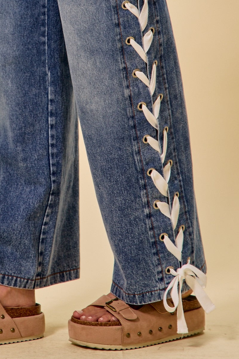 Close-up of blue jeans with white laces and brown sandals on a beige background