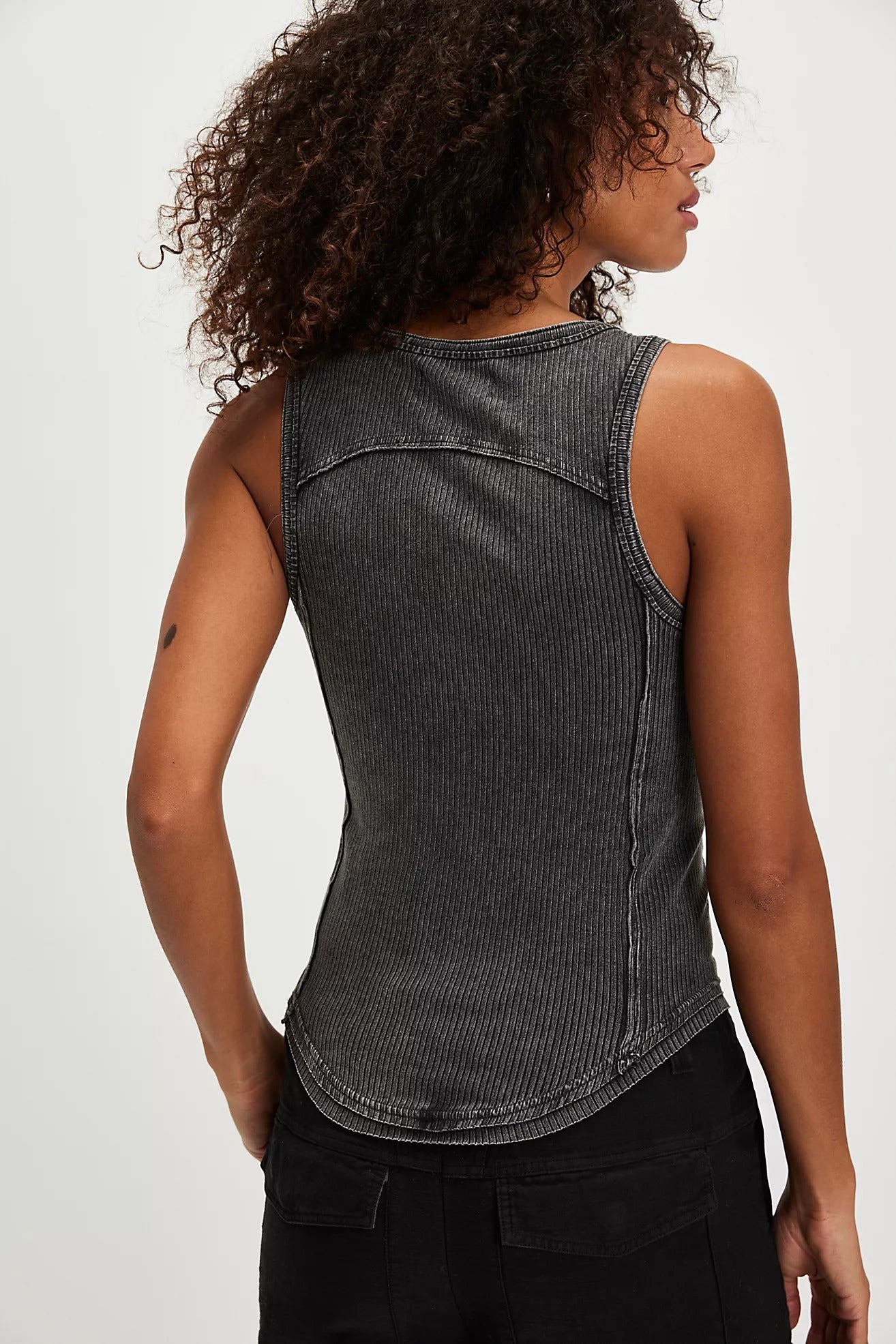Woman wearing a black ribbed tank top against a white background
