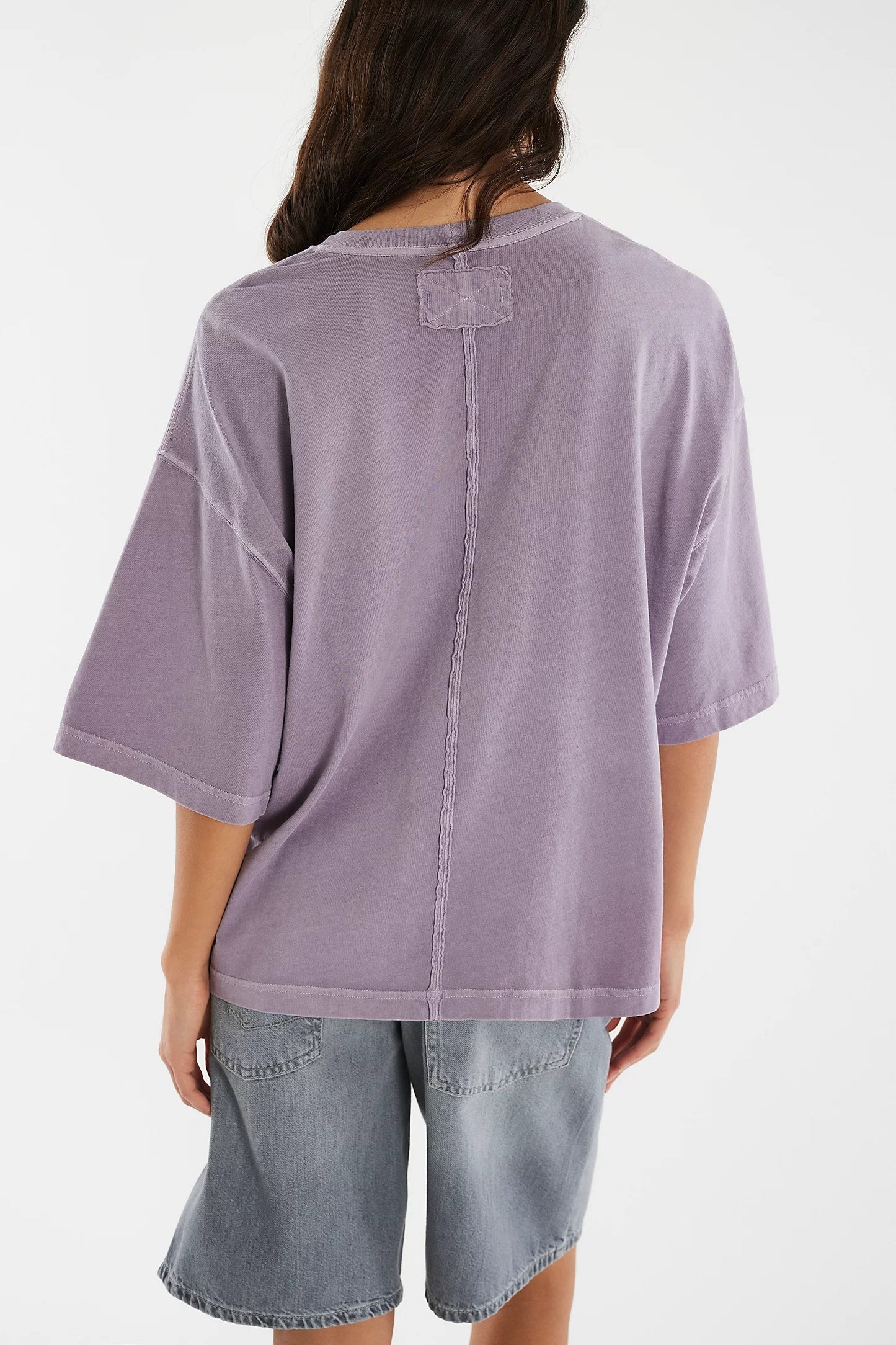 Person wearing a light purple t-shirt and denim shorts on a white background