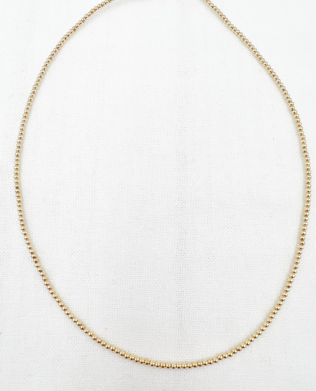 gold necklace on a light grey background