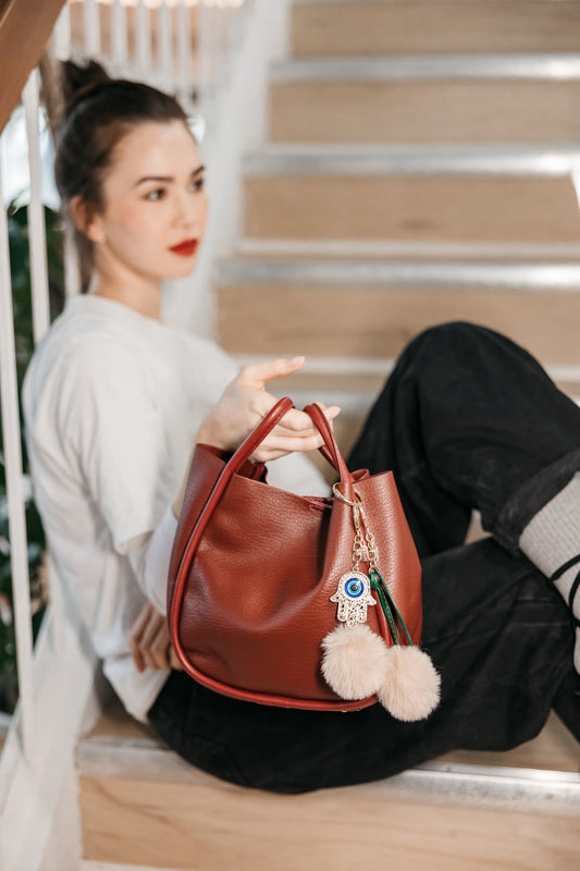 Woman holding a brown leather handbag with decorative elements on a staircase.