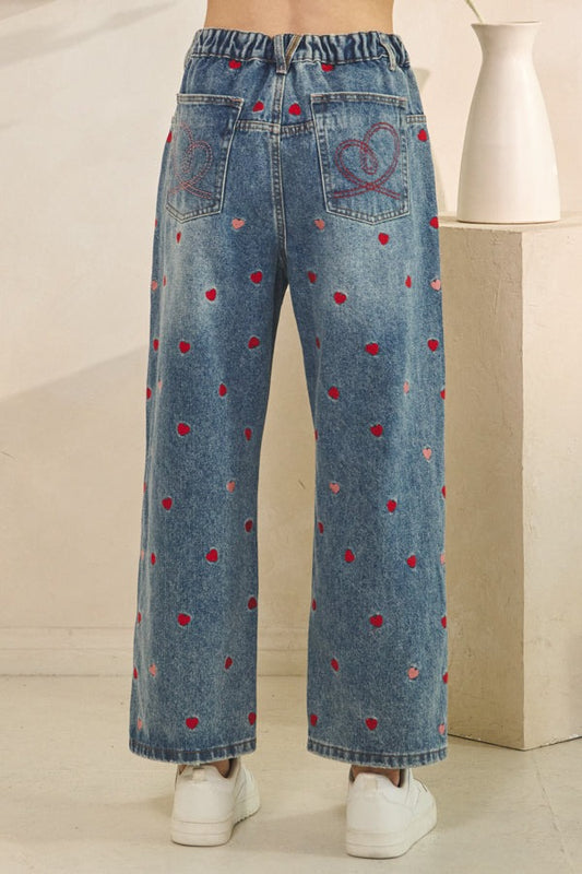 Blue jeans with red polka dot pattern on a neutral background