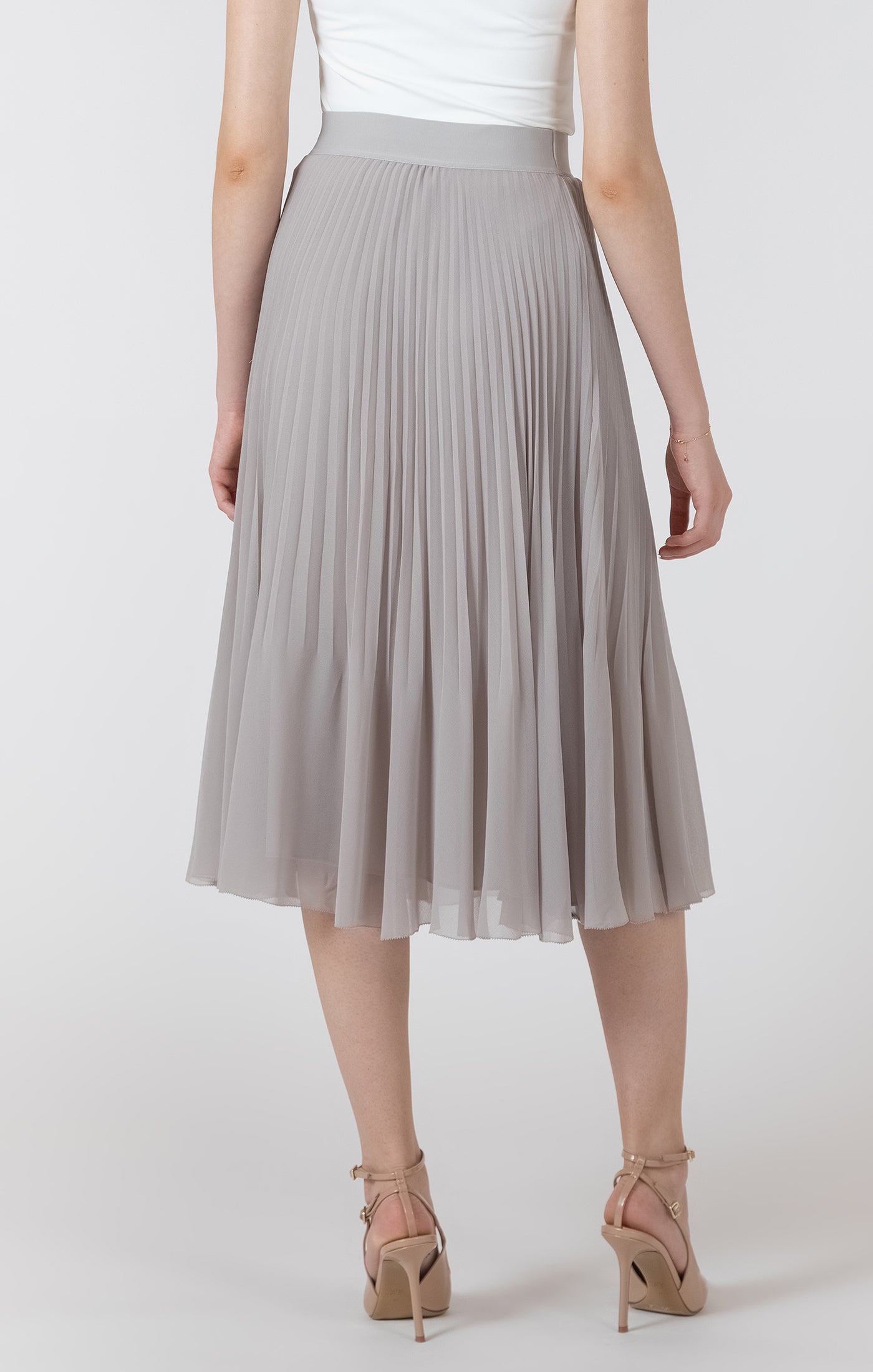 Person wearing a gray pleated skirt on a white background