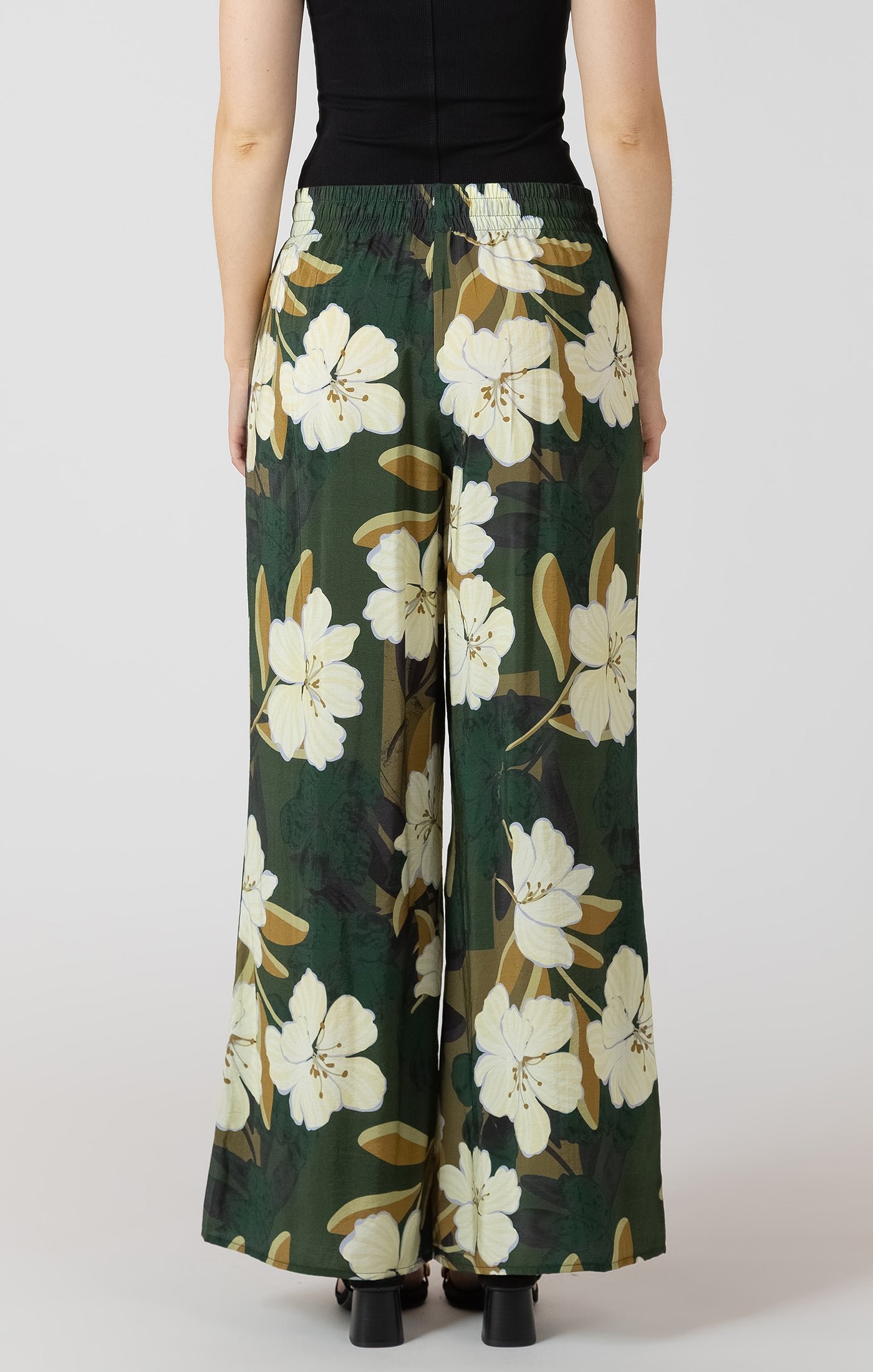 Floral patterned pants worn by a person on a white background