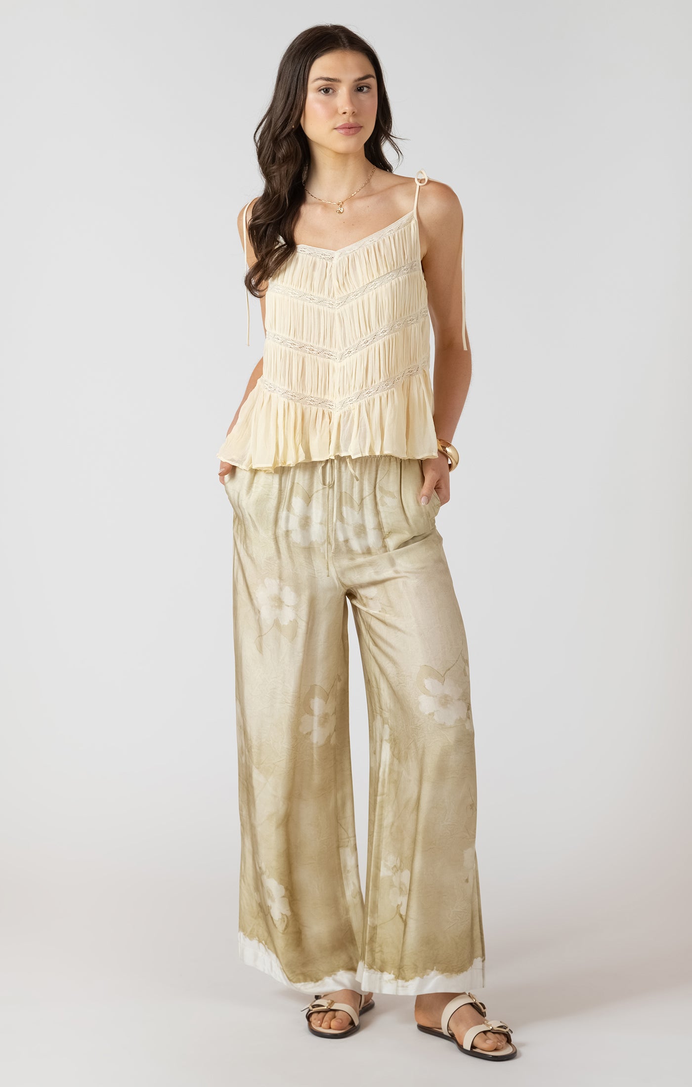 Woman wearing a beige peplum top and wide-leg pants on a white background