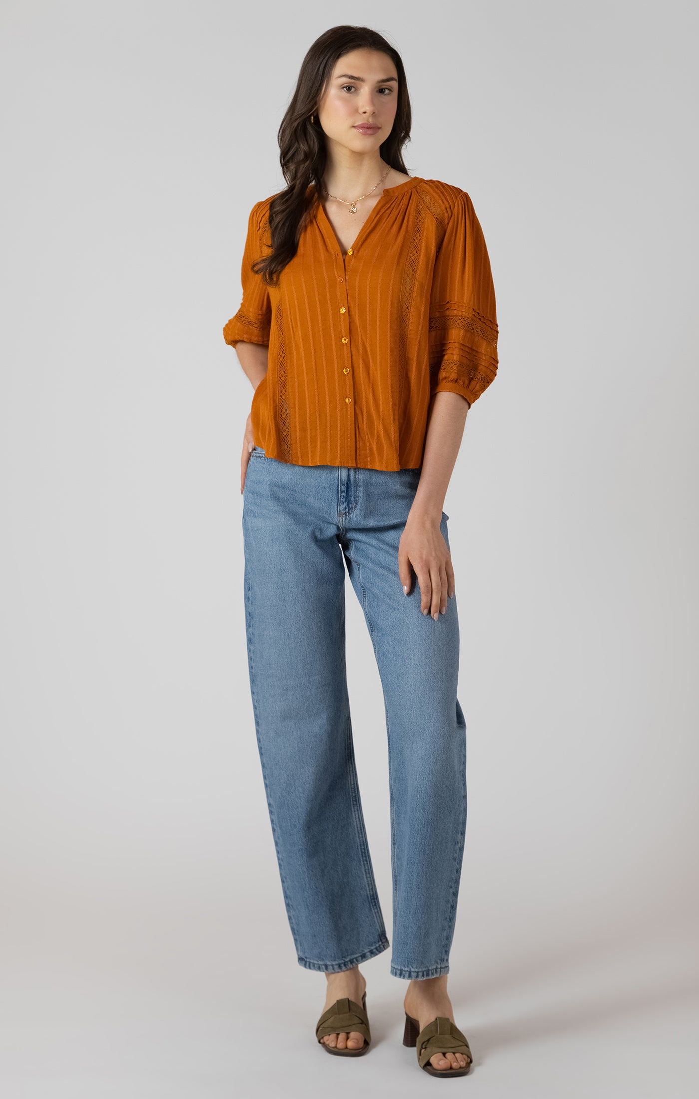 Woman wearing an orange blouse and blue jeans on a white background
