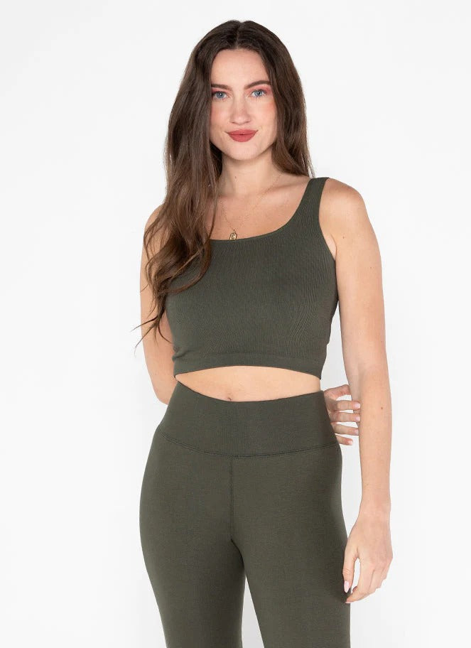 A woman wearing a square neck crop tank in a green color, with the tank displaying a ribbed texture.