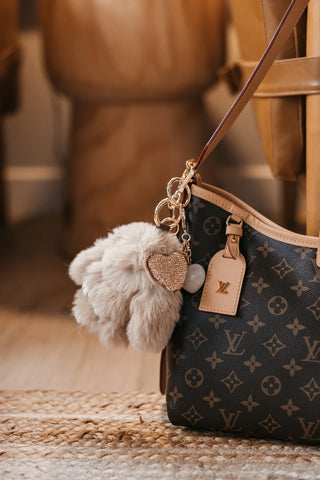 a fuzzy bunny bag charm on a purse in a living room setting. 