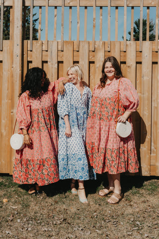 Three women in matching dressing in front a fence.